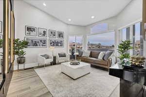 Living room with wood finish floors, recessed lighting, and a high ceiling