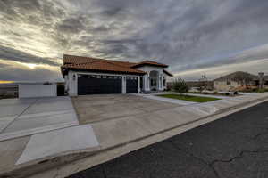 Mediterranean / spanish-style home featuring a tiled roof, driveway, an attached garage, and stucco siding