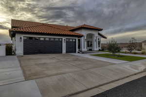Mediterranean / spanish-style home featuring a tiled roof, driveway, stucco siding, and a garage