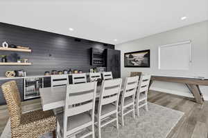Dining area with light wood-style floors, a dry bar, and recessed lighting
