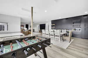 Rec room with light wood-style flooring, beverage cooler, recessed lighting, and a bar