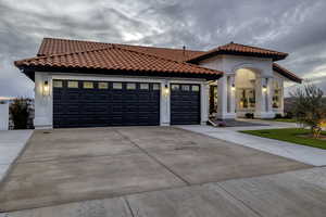Mediterranean / spanish-style house featuring concrete driveway, a tile roof, stucco siding, and a garage
