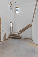 Unfurnished living room with stairs and a high ceiling