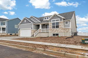 Craftsman-style home featuring stone siding, board and batten siding, roof with shingles, and concrete driveway
