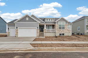 Craftsman-style house featuring stone siding, board and batten siding, a garage, driveway, and roof with shingles