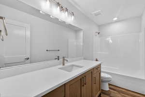 Full bath with vanity, dark wood-style flooring, and shower / tub combination