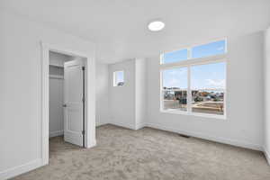Unfurnished bedroom with light colored carpet and a walk in closet