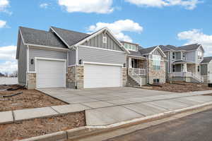 Craftsman house with a garage, concrete driveway, board and batten siding, and stone siding