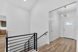 Entrance foyer with light wood-style floors, a chandelier, and lofted ceiling