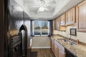 Kitchen with black appliances, dark stone counters, dark wood-type flooring, and a ceiling fan