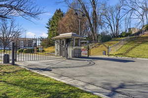 View of asphalt road featuring a gate, curbs, and a gated entry