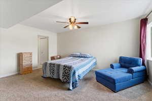 Carpeted bedroom with a ceiling fan and baseboards