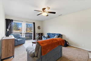 Living room featuring carpet and a ceiling fan