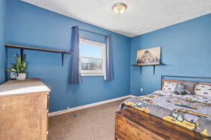 Carpeted bedroom with baseboards and a textured ceiling