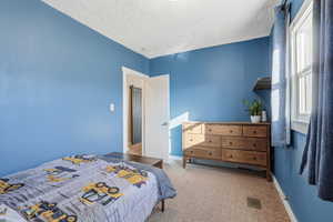 Carpeted bedroom with baseboards and a textured ceiling