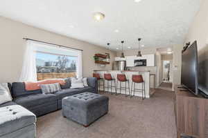 Living area featuring light colored carpet, recessed lighting, and a textured ceiling