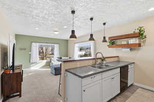 Kitchen with a peninsula, white cabinets, decorative light fixtures, dark countertops, and open floor plan
