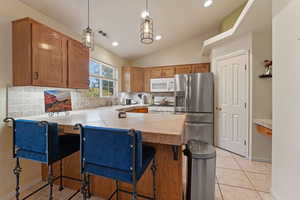 Kitchen with pendant lighting, a kitchen breakfast bar, white appliances, wood finish cabinets, and a peninsula