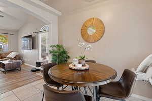 Dining space featuring light tile patterned flooring, lofted ceiling, and arched walkways