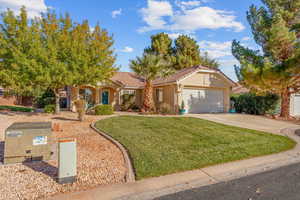 View of front facade with a front lawn, driveway, a tile roof, a garage, and stucco siding