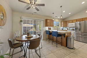 Kitchen featuring stainless steel fridge, wood finish cabinets, decorative light fixtures, a ceiling fan, and a kitchen bar