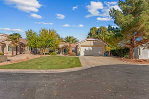 Mediterranean / spanish house featuring driveway, an attached garage, a front yard, stucco siding, and a residential view
