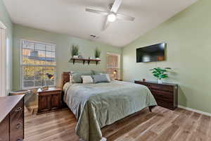 Bedroom with lofted ceiling, light wood-style flooring, and a ceiling fan