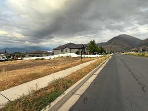 View of asphalt street with a mountain view, sidewalks, and curbs