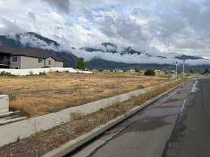 View of asphalt road with a mountain view, sidewalks, and curbs