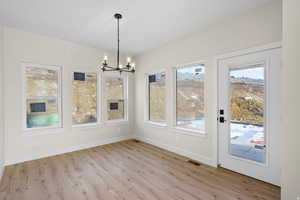 Unfurnished dining area with hanging lights and light wood-style floors