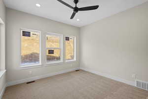 Carpeted empty room featuring a ceiling fan and recessed lighting