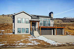 View of front of property featuring a garage, a chimney, concrete driveway, and a mountain view