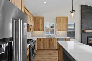 Kitchen featuring high end appliances, light wood-style floors, pendant lighting, lofted ceiling, and backsplash