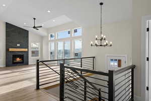 Stairway featuring a premium fireplace, a high ceiling, wood finished floors, a chandelier, and ceiling fan