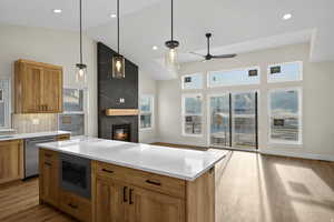 Kitchen with pendant lighting, light wood-style flooring, a fireplace, built in microwave, and wood finish cabinets