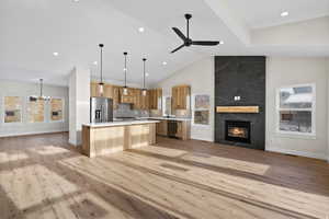 Kitchen with open floor plan, a fireplace, a chandelier, light countertops, and lofted ceiling