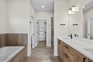 Full bathroom with a walk in closet, double vanity, a stall shower, a bath, and recessed lighting