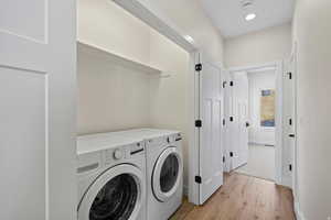 Laundry area with light wood finished floors and washer and dryer