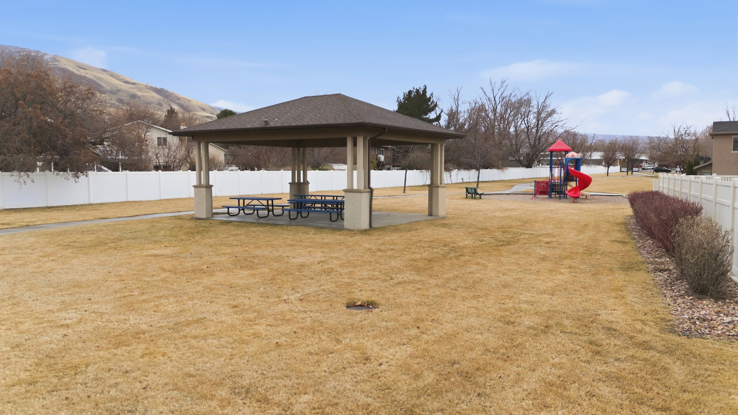 Community park featuring a covered pavilion with picnic tables, a playground structure, and mountain backdrop