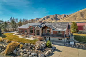 View of front of property featuring brick siding, a chimney, a standing seam roof, and a front lawn