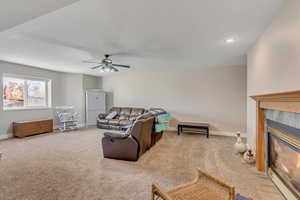 Living room featuring a tiled fireplace, light carpet, a ceiling fan, and recessed lighting