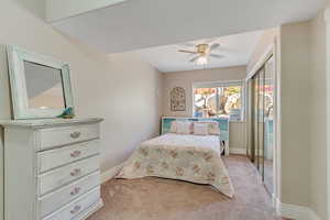 Bedroom featuring light carpet, a ceiling fan, and a closet
