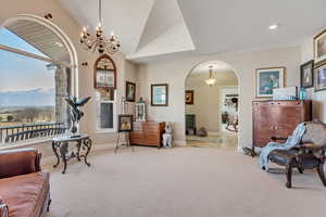 Living area with arched walkways, a mountain view, vaulted ceiling, carpet floors, and hanging lights