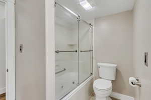 Full bath with shower / bath combination with glass door and toilet