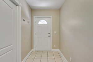 Doorway to outside featuring tile patterned floors and baseboards