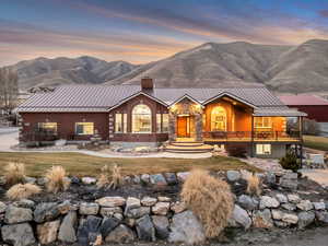 View of front of house featuring a chimney, a standing seam roof, a mountain view, and a front lawn