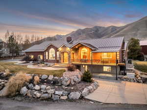 View of front of home with a standing seam roof, a chimney, a mountain view, and stone siding
