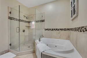 Primary full bathroom featuring a jetted tub and a shower stall