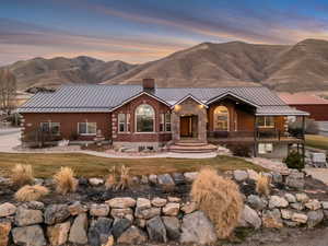 View of front facade with a standing seam roof, a chimney, a mountain view, and brick siding