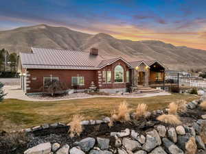 View of front of property featuring a standing seam roof, a front lawn, a mountain view, a chimney, and a patio area